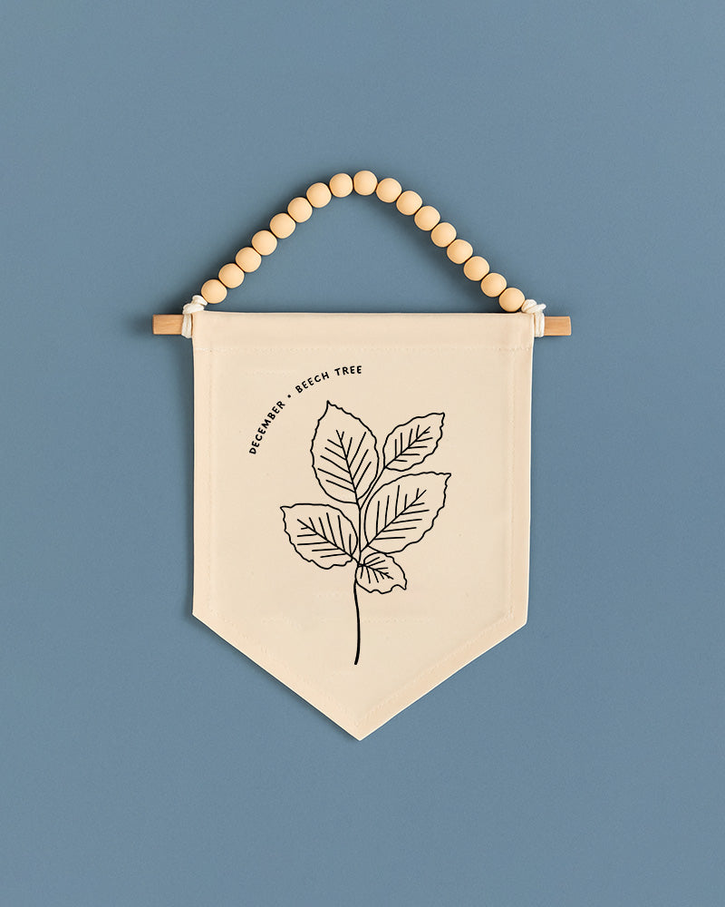 A beige banner with a black leaf design hangs against a blue background.