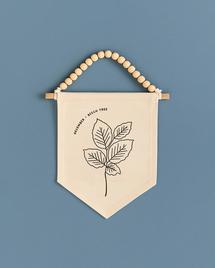 A beige banner with a black leaf design hangs against a blue background.