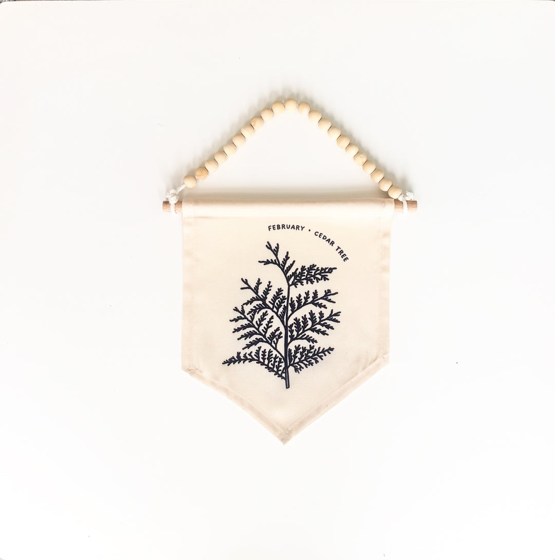 Fabric banner with beaded holder featuring a black leaf design on a white background
