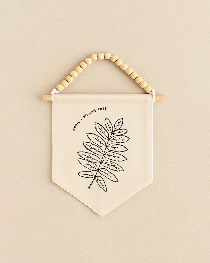 Fabric banner with leaf design and text hanging on a beige wall