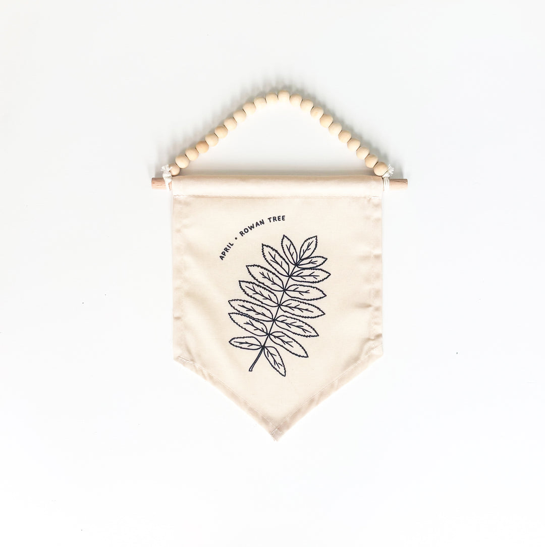 Beige fabric banner with leaf design and wooden beads on a white background