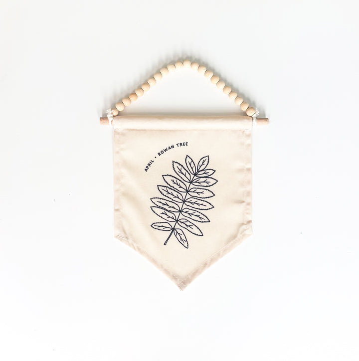 Beige fabric banner with leaf design and wooden beads on a white background