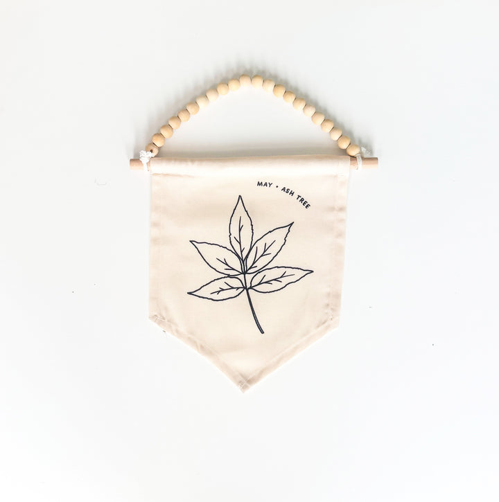 Beige fabric banner with leaf design and wooden beads on a white background