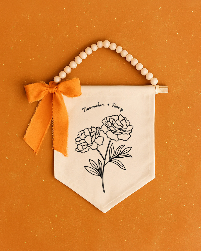 a banner with a floral design and a bow, set against an orange background.