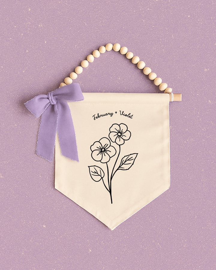 A banner with a floral design and a purple ribbon is displayed against a purple background.